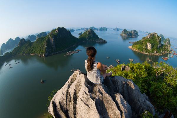 Traveller sitting on the top of mountain in Halong bay and enjoy the beauty of seascape
