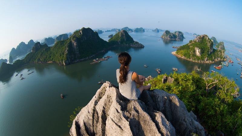 Traveller sitting on the top of mountain in Halong bay and enjoy the beauty of seascape