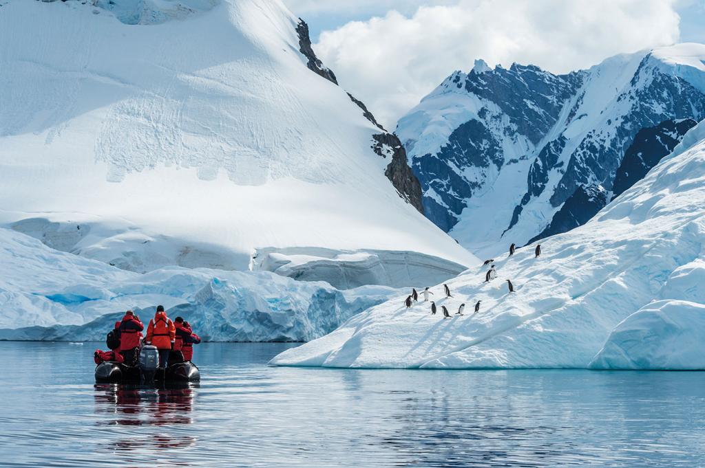 Ponant passengers out on a tender exploring the Antarctic mountainous landscape and penguin wildlife