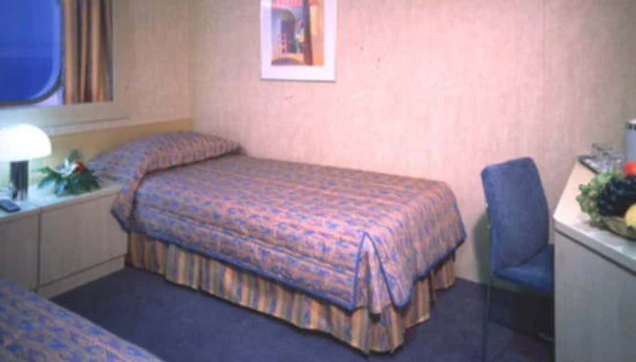 Ship cabin featuring bed and chair with 1990s design